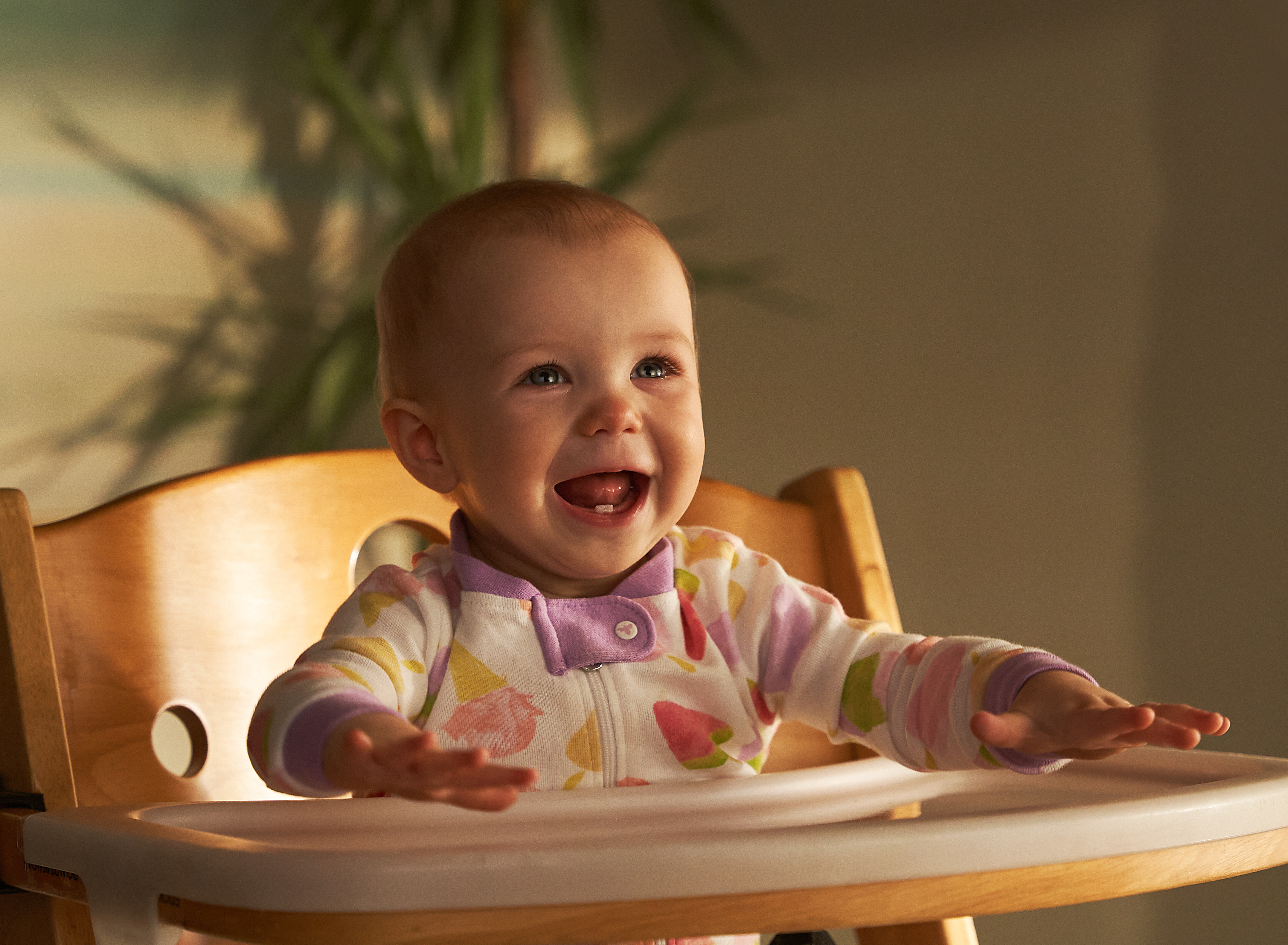 A baby in a highchair, happy, and excited for food. 
